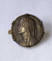 Front view of round brooch showing Virgin Mary profile and inscription
