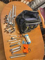 Overview of ratchets, sockets, extensions, wrenches and tool bag on table