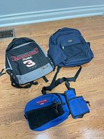 Two backpacks and one waist pack on hardwood floor
