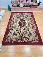 Full view of 5' x 8' burgundy and beige floral medallion rug on hardwood floor