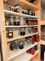 Shelved assortment of filled and empty glass canning jars in various sizes
