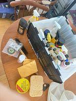 overview of tote with car care products, wax tin, cloth and sponge on table