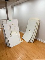 Two groupings of assorted ceiling tile panels leaning against wall