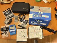 Full kit laid out showing device, accessories, electrodes, manuals, case and box