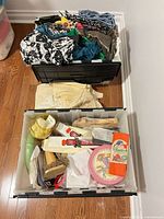 Two black totes on floor, upper tote filled with fabric, lower tote with craft supplies