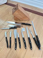Lot overview showing Cutco knife block, nine black-handled Cutco utensils, three wood-handled knives
