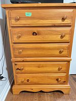 Front view showing five drawers, wood grain, pulls, overall style