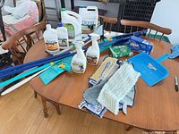 Overall lot on table showing cleaners, mop parts, pads, dustpan