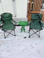 Overall view of two folding chairs and folding table on snow