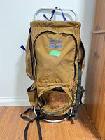 Full view of Jansport tan canvas external frame backpack standing upright