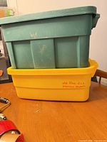 stacked green and yellow Rubbermaid Roughneck totes on table