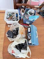 Overview of bins, bags and blue toolbox filled with assorted plumbing fittings and supplies on table
