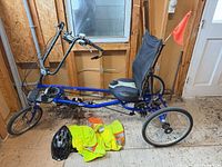 Full view of blue Sun EZ-Tri Classic recumbent trike with seat, handlebars, safety flag, helmet and vests