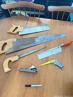All six woodworking tools laid out on table: block plane, panel saw, backsaw, flush-cut saw, keyhole saw, mini saw