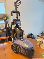 Front view showing pressure washer body, wheels, handle, hose reel