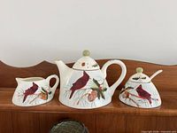 Teapot, creamer and sugar bowl set displaying cardinal design
