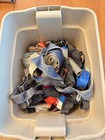 Tote containing assorted coloured tie-down straps with metal hardware