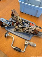 Group shot of spokeshave, three bench planes and hand brace on table