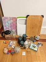 All items grouped: cutting boards, coffee carafe, glass bottles, candle holder with candles, seashells, ornaments, decorative sphere, napkins, mug, ceramic flower