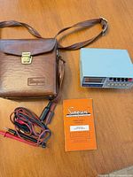 Overall lot showing multimeter, leather case, leads, manual