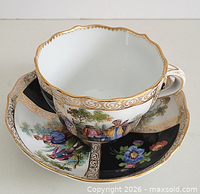 Cup and saucer front view showing hand painted figurative and floral panels