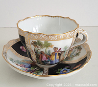 Cup displayed on saucer showing hand painted panels and gilt trim
