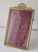 Front angled view showing brass frame, glass, ribbon crest