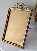 Front angled view showing brass frame, ribbon crest, easel stand
