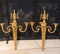 Full pair of gold-tone metal 3-light wall sconces in front of fireplace screen