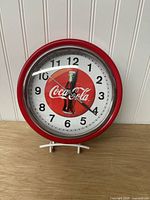 Front view of red Coca-Cola wall clock showing dial and hands