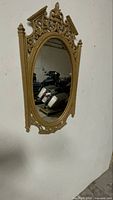Front view of ornate gold oval wall mirror on wall