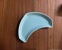 Top view of pale blue crescent dish on wood surface