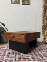 Front view showing teak top, drawer front, black pedestal legs