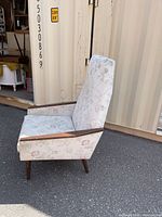 Side view showing full profile, wood arms, floral upholstery, tapered legs