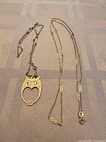 Two gold necklaces laid flat showing owl pendant and link styles