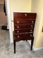 Front view of dark wood five-drawer jewelry chest