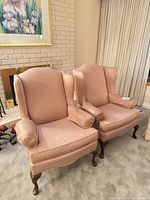 Front view of both matching pink wingback armchairs
