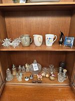 Overview of two shelves showing crystal pieces, shakers, mugs, candleholders