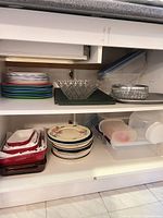 Overview of cabinet shelves showing bakeware, plates, glass bowls and plastic containers
