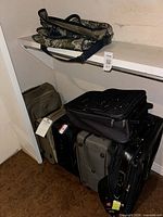 Group of assorted suitcases and camouflage bag on shelf