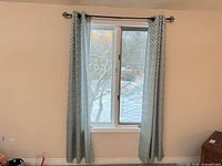 Blue patterned curtains hanging from decorative rod on window