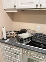 Overview of all bakeware, grill, wire basket, paper towel holder and grater on countertop
