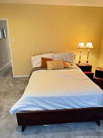 Bed frame assembled with mattress showing mahogany footboard, side rails, headboard partially visible