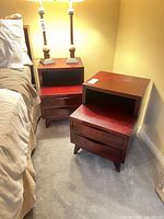 Two matching mahogany side tables next to bed showing overall design and wear