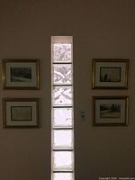 All four framed watercolours hung beside glass block window