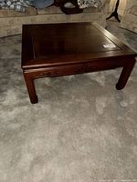 Full view of dark wood square coffee table on carpet