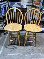 Front view of two matching light wood swivel bar stools