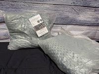 Two vacuum-sealed grey weighted blankets on black cloth