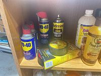Shelf with three WD-40 cans, Admire polish, roll of tape and packaging
