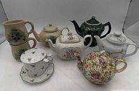 Group view of all seven ceramic teapots and pitchers